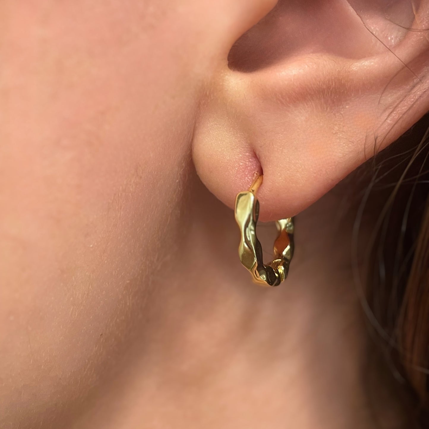 Gold hoop earring worn on an ear